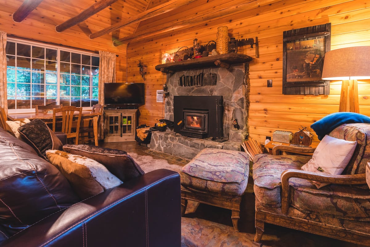 Warm timber living room with a glowing wood-burning fireplace