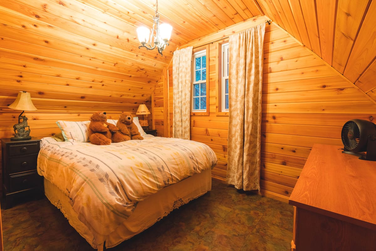 Upstairs queen bedroom with sloped timber ceiling
