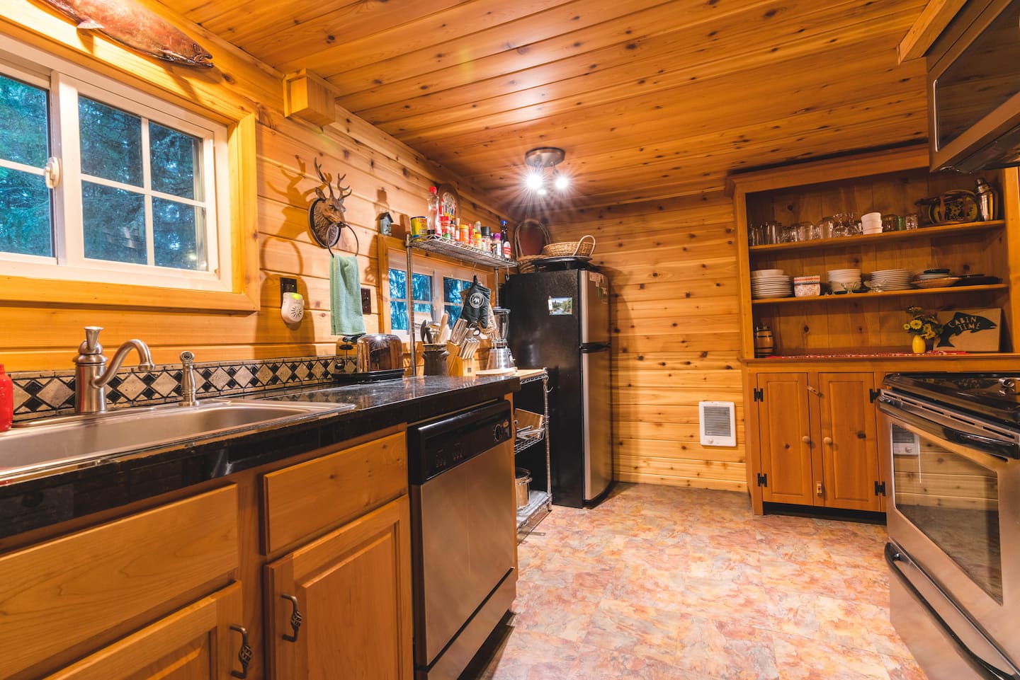 Kitchen with wood cabinetry, range, sink, and open shelving